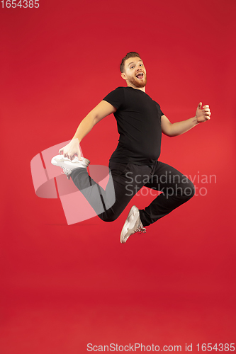 Image of Full length portrait of young successfull high jumping man gesturing isolated on red studio background