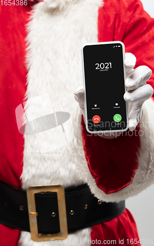 Image of Close up hands of Santa Claus holding device with incoming call from 2021 year