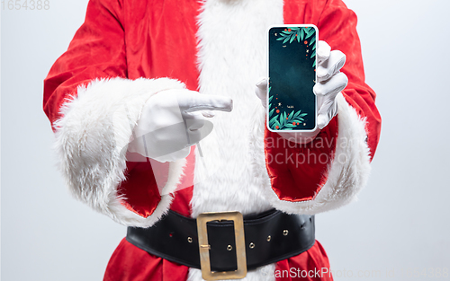 Image of Close up hands of Santa Claus holding device with stylish decoration on the screen, copyspace