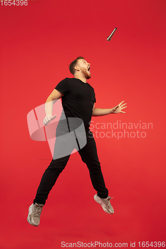 Image of Full length portrait of young successfull high jumping man gesturing isolated on red studio background