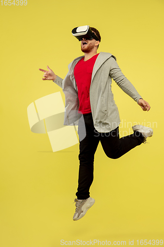 Image of Full length portrait of young successfull high jumping man gesturing isolated on yellow studio background