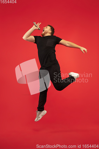 Image of Full length portrait of young successfull high jumping man gesturing isolated on red studio background