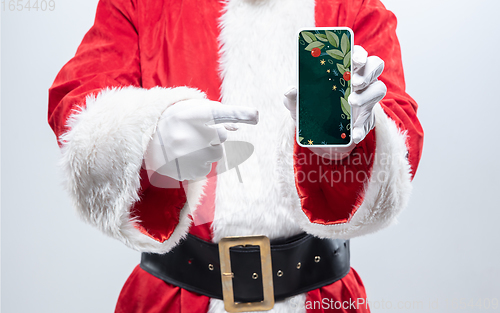 Image of Close up hands of Santa Claus holding device with stylish decoration on the screen, copyspace