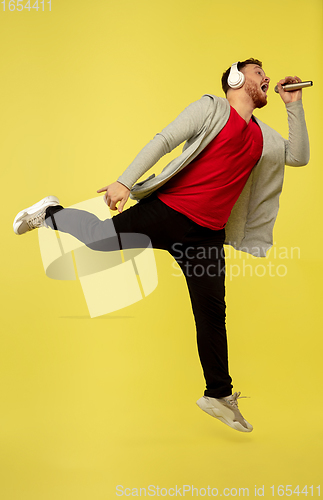 Image of Full length portrait of young successfull high jumping man gesturing isolated on yellow studio background