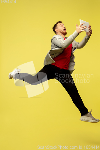 Image of Full length portrait of young successfull high jumping man gesturing isolated on yellow studio background