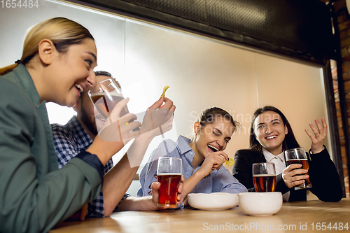 Image of Happy co-workers celebrating corporate event after tensioned work day. Look delighted, friendly, cheerful