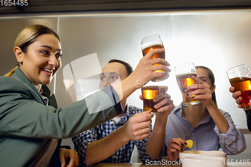 Image of Happy co-workers celebrating corporate event after tensioned work day. Look delighted, friendly, cheerful