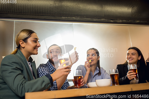 Image of Happy co-workers celebrating corporate event after tensioned work day. Look delighted, friendly, cheerful