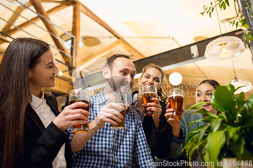 Image of Happy co-workers celebrating corporate event after tensioned work day. Look delighted, friendly, cheerful