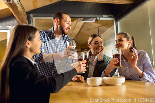 Image of Happy co-workers celebrating corporate event after tensioned work day. Look delighted, friendly, cheerful