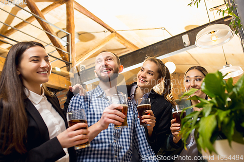 Image of Happy co-workers celebrating corporate event after tensioned work day. Look delighted, friendly, cheerful