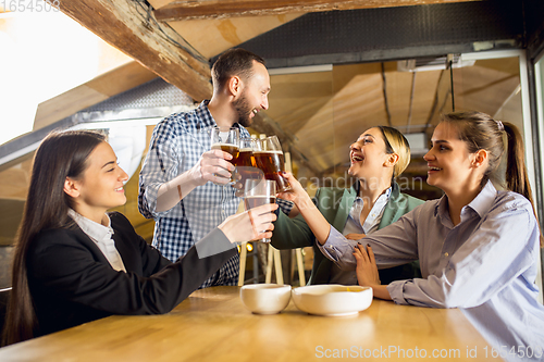 Image of Happy co-workers celebrating corporate event after tensioned work day. Look delighted, friendly, cheerful