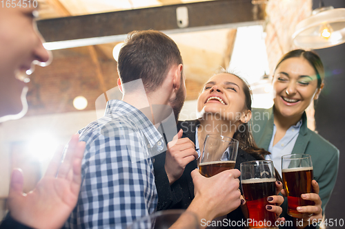 Image of Happy co-workers celebrating corporate event after tensioned work day. Look delighted, friendly, cheerful