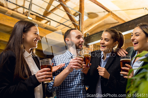 Image of Happy co-workers celebrating corporate event after tensioned work day. Look delighted, friendly, cheerful