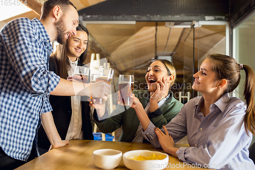 Image of Happy co-workers celebrating corporate event after tensioned work day. Look delighted, friendly, cheerful