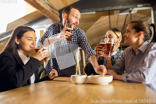 Image of Happy co-workers celebrating corporate event after tensioned work day. Look delighted, friendly, cheerful