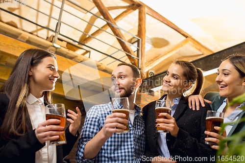 Image of Happy co-workers celebrating corporate event after tensioned work day. Look delighted, friendly, cheerful