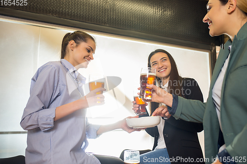 Image of Happy co-workers celebrating corporate event after tensioned work day. Look delighted, friendly, cheerful