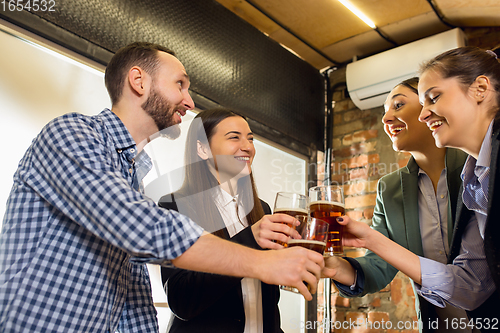 Image of Happy co-workers celebrating corporate event after tensioned work day. Look delighted, friendly, cheerful