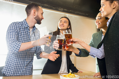 Image of Happy co-workers celebrating corporate event after tensioned work day. Look delighted, friendly, cheerful