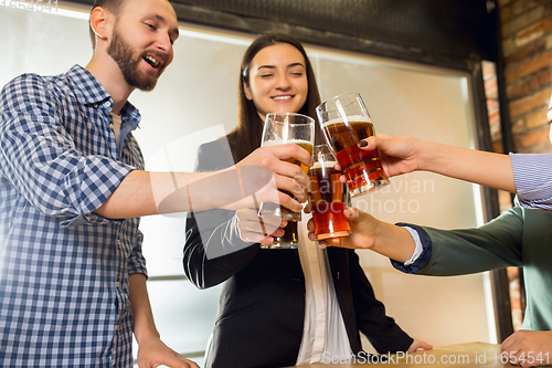 Image of Happy co-workers celebrating corporate event after tensioned work day. Look delighted, friendly, cheerful