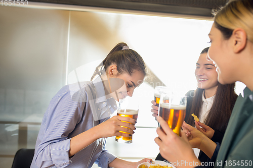 Image of Happy co-workers celebrating corporate event after tensioned work day. Look delighted, friendly, cheerful