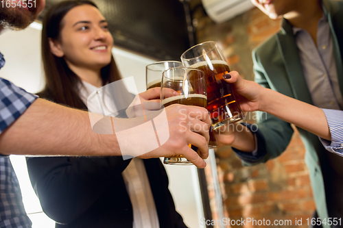 Image of Happy co-workers celebrating corporate event after tensioned work day. Look delighted, friendly, cheerful