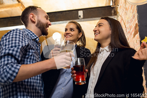 Image of Happy co-workers celebrating corporate event after tensioned work day. Look delighted, friendly, cheerful