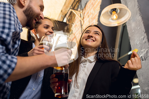 Image of Happy co-workers celebrating corporate event after tensioned work day. Look delighted, friendly, cheerful