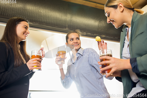 Image of Happy co-workers celebrating corporate event after tensioned work day. Look delighted, friendly, cheerful