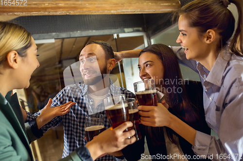 Image of Happy co-workers celebrating corporate event after tensioned work day. Look delighted, friendly, cheerful