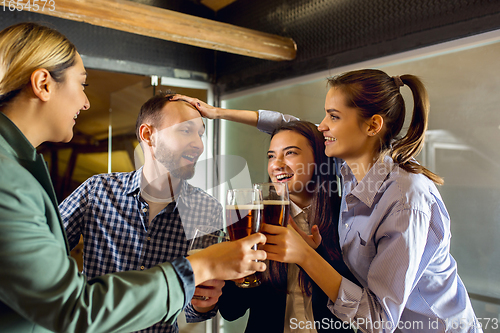 Image of Happy co-workers celebrating corporate event after tensioned work day. Look delighted, friendly, cheerful