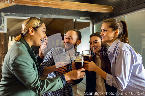 Image of Happy co-workers celebrating corporate event after tensioned work day. Look delighted, friendly, cheerful