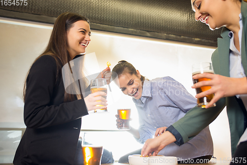 Image of Happy co-workers celebrating corporate event after tensioned work day. Look delighted, friendly, cheerful