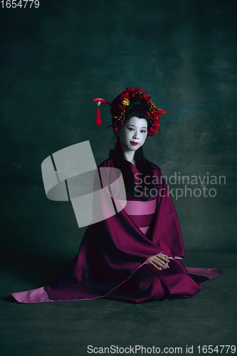 Image of Young japanese woman as geisha on dark green background. Retro style, comparison of eras concept.