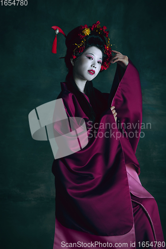 Image of Young japanese woman as geisha on dark green background. Retro style, comparison of eras concept.