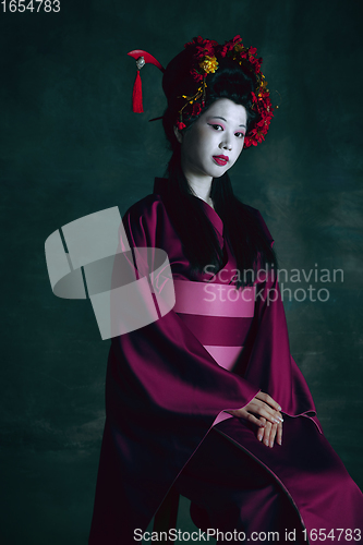 Image of Young japanese woman as geisha on dark green background. Retro style, comparison of eras concept.