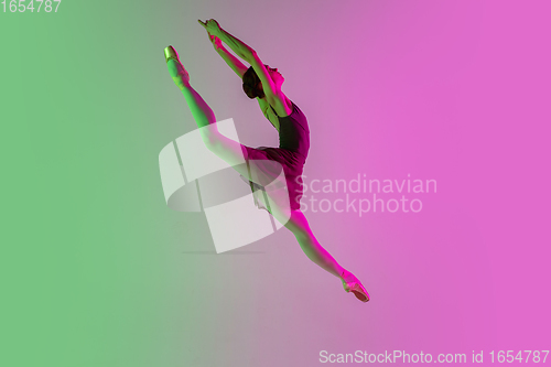 Image of Young and graceful ballet dancer isolated on gradient pink-green studio background in neon light. Art in motion