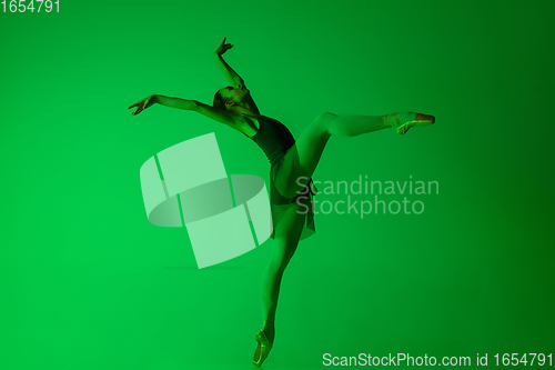 Image of Young and graceful ballet dancer isolated on gradient green studio background in neon light. Art in motion