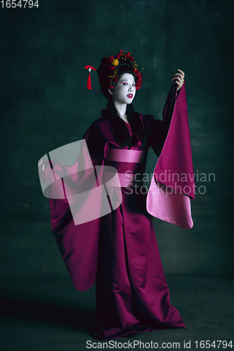 Image of Young japanese woman as geisha on dark green background. Retro style, comparison of eras concept.