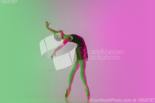 Image of Young and graceful ballet dancer isolated on gradient pink-green studio background in neon light. Art in motion