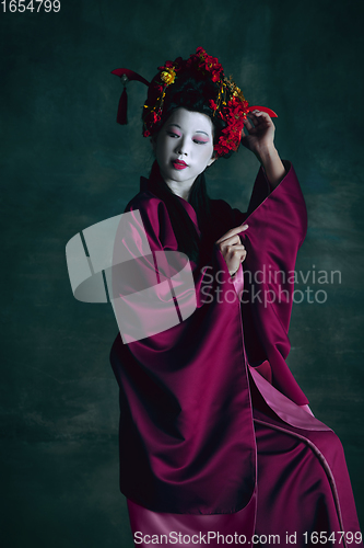 Image of Young japanese woman as geisha on dark green background. Retro style, comparison of eras concept.