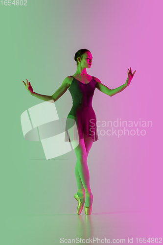 Image of Young and graceful ballet dancer isolated on gradient pink-green studio background in neon light. Art in motion
