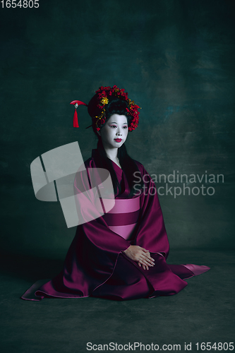 Image of Young japanese woman as geisha on dark green background. Retro style, comparison of eras concept.