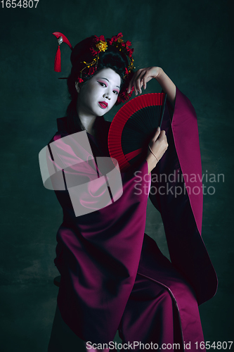 Image of Young japanese woman as geisha on dark green background. Retro style, comparison of eras concept.