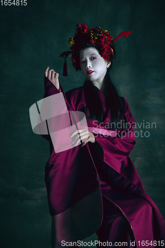 Image of Young japanese woman as geisha on dark green background. Retro style, comparison of eras concept.