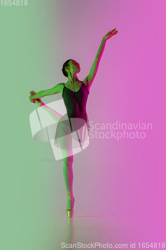 Image of Young and graceful ballet dancer isolated on gradient pink-green studio background in neon light. Art in motion