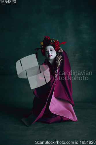 Image of Young japanese woman as geisha on dark green background. Retro style, comparison of eras concept.