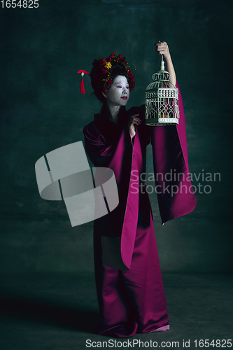 Image of Young japanese woman as geisha on dark green background. Retro style, comparison of eras concept.