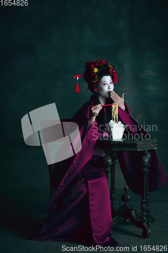 Image of Young japanese woman as geisha on dark green background. Retro style, comparison of eras concept.